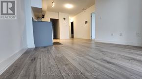 Burlington (Alton) condo for rent - A spacious room with wooden flooring and a grey refrigerator.