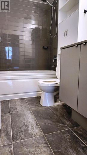 Burlington (Alton) condo for rent - A white toilet sits in a bathroom with a tiled shower area.