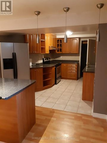 Brampton (Bram East) apartment for rent - A kitchen with wooden cabinets and a black fridge.