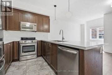 Hamilton (Waterdown) townhouse for rent - A kitchen with brown cabinets and a stainless steel dishwasher.