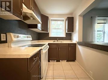 London East (East F) multi-family for rent - A kitchen with brown cabinets and a white dishwasher.