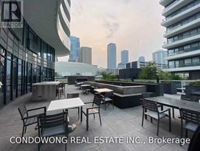 Toronto (Church-Yonge Corridor) condo for rent - A rooftop patio with chairs and tables overlooking a city skyline.