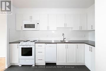 Toronto (Westminster-Branson) house for rent - A white kitchen with a black counter top and a sink.