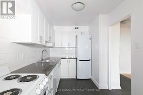 Toronto (Westminster-Branson) house for rent - A white kitchen with a stove top oven and a refrigerator.