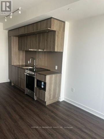 Mississauga (City Centre) condo for rent - A modern kitchen with wooden cabinets and a stainless steel sink.