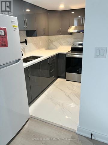 Brampton (Credit Valley) apartment for rent - A kitchen with a white fridge and black cabinets.