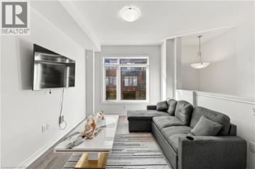 Hamilton condo for rent - A modern living room with a grey sofa and a flat screen TV mounted on the wall.