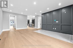 Innisfil (Stroud) apartment for rent - A spacious room with wooden flooring and a large grey wardrobe with a blue sign on it.