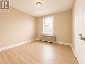 Toronto (Beechborough-Greenbrook) multi-family for rent - A room with a white door, a window with blinds, and a radiator on the wall.