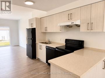 Welland (Broadway) townhouse for rent - A kitchen with black appliances and wooden cabinets.