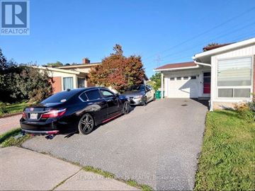 Ottawa apartment for rent - A black car is parked in front of a house with a garage.