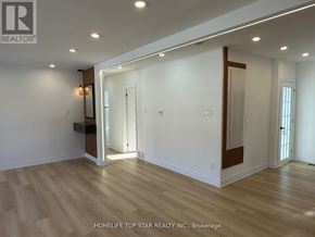 Richmond Hill (Crosby) apartment for rent - A spacious room with wooden flooring and white walls, with a doorway leading to another room.