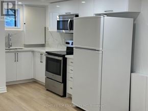 Richmond Hill (Crosby) apartment for rent - A white refrigerator stands in a kitchen with white cabinets and a black countertop.