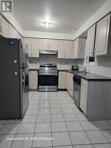 Toronto (Eglinton East) townhouse for rent - A kitchen with a black fridge and white cabinets.