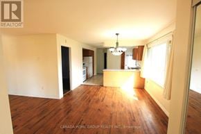 Innisfil apartment for rent - A large empty room with wood flooring and a chandelier.