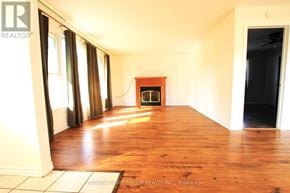 Innisfil apartment for rent - A room with wooden floors and a fireplace in the middle.