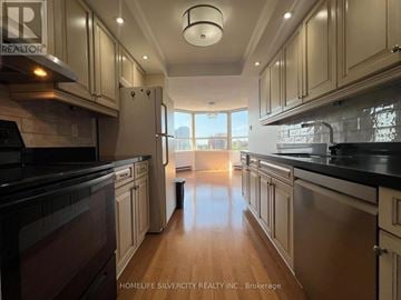 Brampton (Downtown Brampton) condo for rent - A kitchen with wooden cabinets and black countertops.