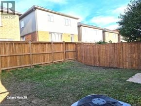 Niagara Falls apartment for rent - A backyard with a wooden fence and a Galaxy Note 20 phone in the foreground.