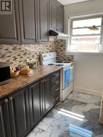 Brampton (Brampton South) apartment for rent - A kitchen with a white stove top oven and dark wood cabinets.
