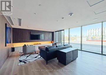 Toronto (Waterfront Communities) condo for rent - A modern living room with a large sectional sofa and a flat screen TV.