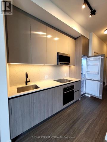 Toronto (Waterfront Communities) condo for rent - A modern kitchen with a sink, stove, and refrigerator.
