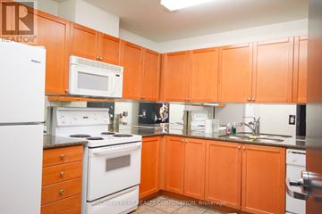 Toronto (Willowdale East) condo for rent - A kitchen with orange cabinets and a white fridge.