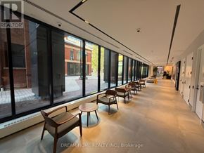 Toronto (North St. James Town) condo for rent - A long hallway with tables and chairs on the side.