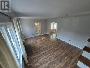 Niagara Falls (Dorchester) apartment for rent - A room with wooden flooring and white walls, with a window on the left and a door on the right.