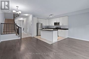 Ottawa townhouse for rent - A spacious kitchen and living room with white cabinets and a staircase.