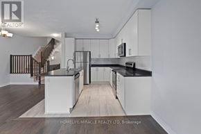Ottawa townhouse for rent - A modern kitchen with white cabinets and a black countertop.