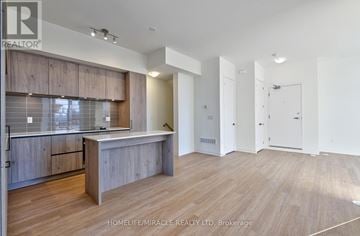 Richmond Hill townhouse for rent - A spacious room with wooden flooring and a kitchen area with a counter and cabinets.