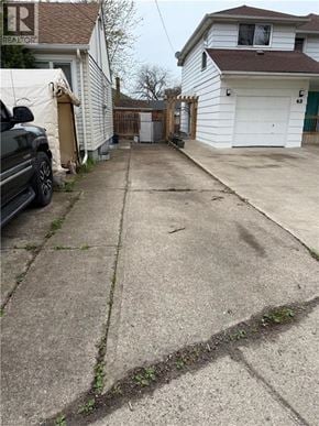 St. Catharines apartment for rent - A concrete driveway leads to a white garage with a black car parked on the left side.