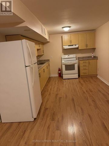 Brampton (Northwest Sandalwood Parkway) apartment for rent - A white refrigerator stands in a kitchen with wooden floors and cabinets.