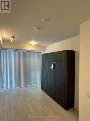 Toronto (Waterfront Communities) condo for rent - A room with a wooden floor and a dark brown wardrobe.