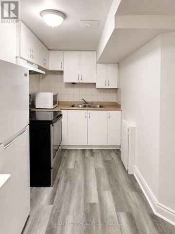 Mississauga (Churchill Meadows) townhouse for rent - A kitchen with white cabinets and a black fridge.
