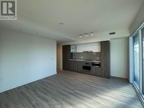 Toronto (Waterfront Communities) condo for rent - A spacious living room with a kitchen area in the background.