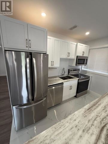 Hamilton (Ancaster) apartment for rent - A modern kitchen with a stainless steel refrigerator and white cabinets.