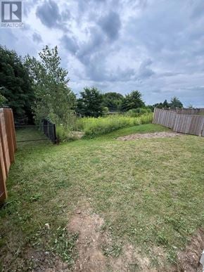 Hamilton (Ancaster) apartment for rent - A backyard with a wooden fence and a grassy area.