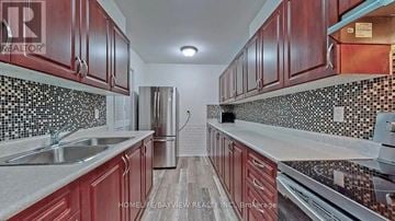Toronto (Crescent Town) condo for rent - A kitchen with red cabinets and a black and white tiled backsplash.
