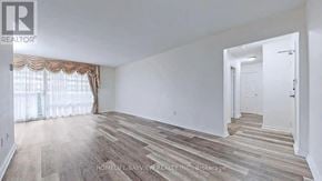 Toronto (Crescent Town) condo for rent - A spacious room with wooden flooring and white walls.