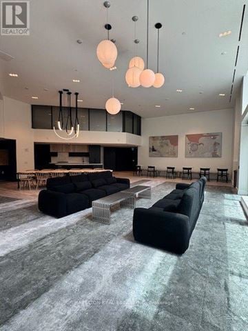 Toronto (Junction Area) condo for rent - A modern living room with a black sofa and a grey carpet.