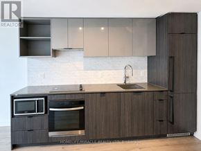 Toronto (Church-Yonge Corridor) condo for rent - A modern kitchen with dark wood cabinets and a white subway tile backsplash.