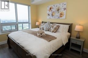 Markham (Unionville) condo for rent - A bedroom with a large bed and a view of the city.