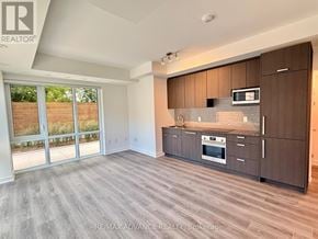 Toronto (Parkwoods-Donalda) townhouse for rent - A spacious kitchen with dark wood cabinets and a stainless steel oven.