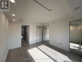 Toronto (Bathurst Manor) condo for rent - A spacious room with a slanted ceiling and a large mirror on the wall.