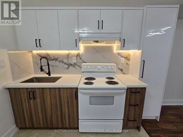 Toronto (New Toronto) apartment for rent - A kitchen with a white stove and wooden cabinets.
