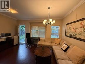 Burnaby apartment for rent - A living room with a brown floor and a chandelier hanging from the ceiling.