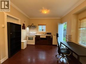 Burnaby apartment for rent - A kitchen area with a black fridge, a white oven, and a black chair.