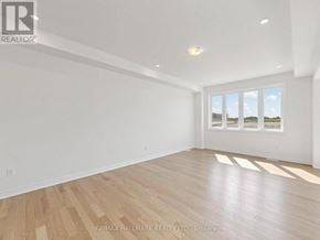 Whitby (Brooklin) apartment for rent - A spacious room with wooden flooring and a large window.