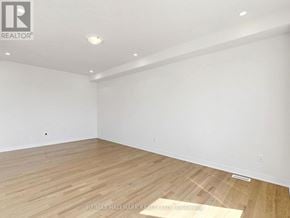 Whitby (Brooklin) apartment for rent - A spacious room with wooden flooring and white walls.